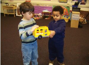 Boy sharing a toy truck with his friend