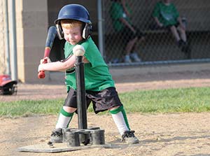 A boy trying to hit a baseball off of a batting tee