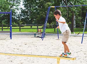 A boy walking on a playground balance beam