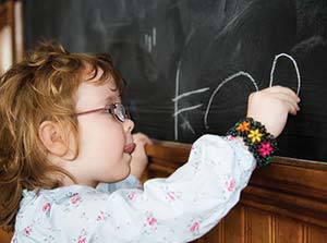 Child Writing her name on chalkboard