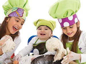 Picture of three children in chef's hats playing with dough