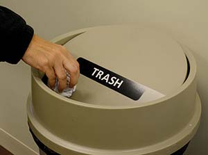 Picture of a person putting trash in a trashcan