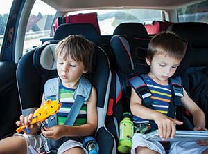 Two young boys in car seats playing with toys