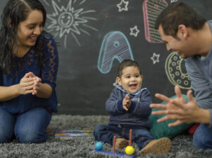 Toddler clapping hands with caregiver