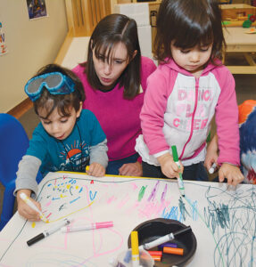 Children making marks on a table covered with paper