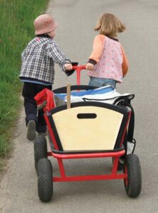 Two children work together to pull a wagon