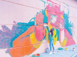 Women painting mural on wall