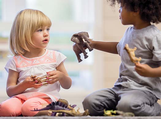 Two girls playing together and sharing animal toys