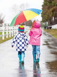 Two children share an umbrella on a rainy day