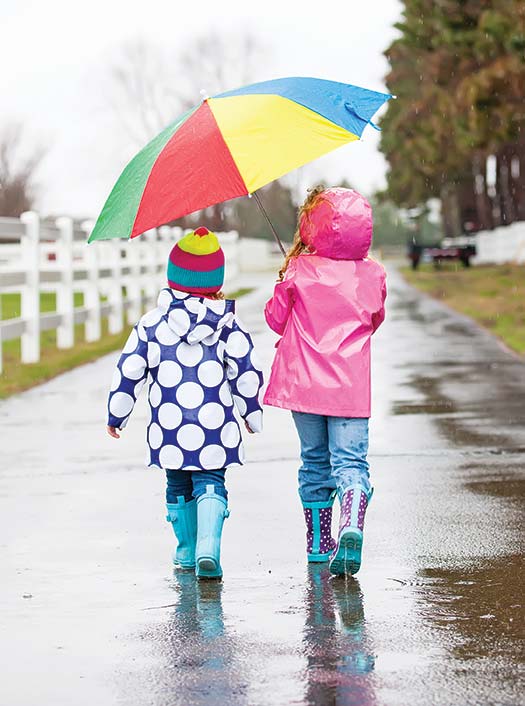 Two children share an umbrella on a rainy day